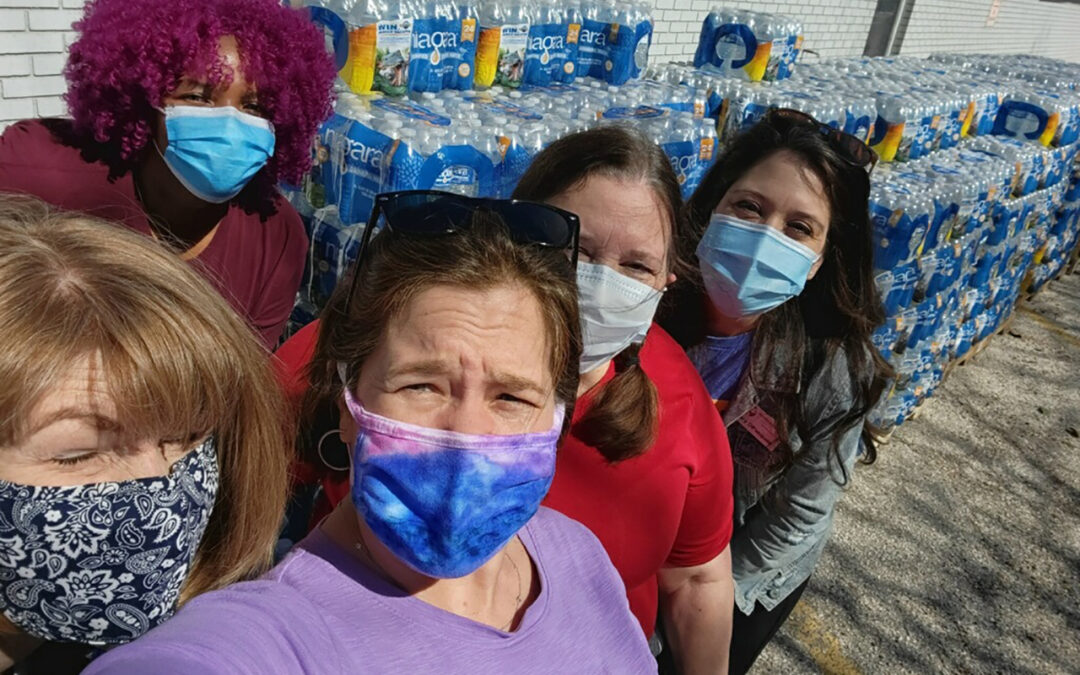 Staff posing with cases of water